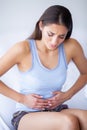 Stomach Pain. Unhealthy young woman with stomachache leaning on the bed at home Royalty Free Stock Photo