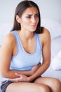Stomach Pain. Unhealthy young woman with stomachache leaning on the bed at home Royalty Free Stock Photo