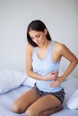 Stomach Pain. Unhealthy young woman with stomachache leaning on the bed at home Royalty Free Stock Photo