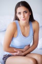 Stomach Pain. Unhealthy young woman with stomachache leaning on the bed at home Royalty Free Stock Photo