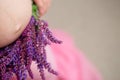 Stomach of the pregnant woman in a frame of lilac flowers