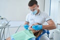 Professional dentist treating dental caries in teenager