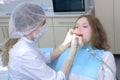 Stomatologist is cleaning girl`s teeth using electric toothbrush in dentistry.