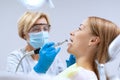 Stomatologist in mask and gloves brushing teeth to patient