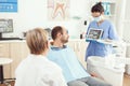 Stomatologist nurse in gloves holding tablet showing jaw x-ray to sick patient