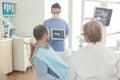 Stomatologist nurse showing tooth x-ray to sick patient explaining treatment