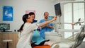 Stomatologist pointing on digital screen explaining x-ray to mother Royalty Free Stock Photo