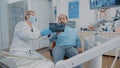 Stomatologist showing denture x ray results to patient at checkup visit