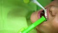 Stomatologist washing patient teeth with irrigator after bleaching procedure