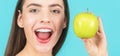 Stomatology concept. Woman with perfect smile holding apple, blue background. Woman eat green apple. Portrait of young