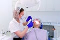 Dentist cures teeth of young woman in stomatology clinic, treatment procedure.