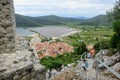 A group of tourists walking up and down the stairs along the Walls of Ston with the ancient town of Ston, Croatia below