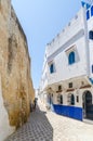 Stone alley with historic city wall and white and blue washed buildings in Asilah, Morocco, North Africa Royalty Free Stock Photo