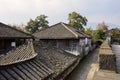 Stone alleyway between ancient tile-roofed buildings and wall in cloudy afternoon