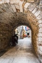 Stone arch connecting the old medieval streets of Trogir in Croatia with a motorcycle and the flag of Croatia