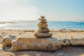 Stone balance, pyramid of pebbles on the beach. Turquoise colored sea waves and clear blue sky Royalty Free Stock Photo