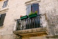 Stone balcony with a wrought iron lattice with flowerpots on the stone facade of the house Royalty Free Stock Photo