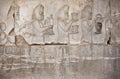 Stone bas-relief with ancient people holding food and edged weapons in Persepolis, Iran