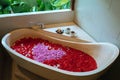 Stone bath tub with heart shaped flower petals near window with jungle view. Organic spa relaxation in luxury Bali Royalty Free Stock Photo
