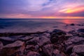 Stone beach and calm sea at dusk with purple sunset sky. Tropical sea. Skyline in the evening with golden, purple, and red sky. Royalty Free Stock Photo