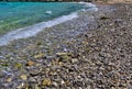 Stone beach low angle view, pebbles  turquoise sea wate and snorkeler swimming Royalty Free Stock Photo