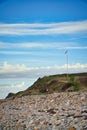 Stone beach by the sea. Flagpole with Danish flag on a hill. Danish coast