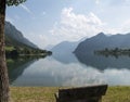 Stone bench and panoramic view with mountains reflected on water Royalty Free Stock Photo