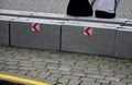 Stone blocks connected by metal strips. The unit acts as a road barrier with traffic arrows in a bend. A heavy chain protects the Royalty Free Stock Photo