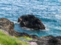 A stone among the blue sea waves in spring. Seaside landscape. Coastal cliffs of the Atlantic, rock formation beside body of water