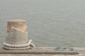 Stone bollard with rope on boat dock and sea Royalty Free Stock Photo