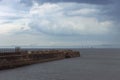 Heugh breakwater pier in stormy, cloudy weather with wind farm behind