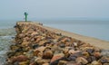 Stone breakwater with green lighthouse in a small harbor Royalty Free Stock Photo