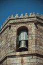 Stone brick wall and bronze bell on steeple at the Cathedral of Guarda