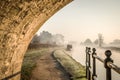 Stone bridge beautiful foggy misty canal narrow boat sunrise with smoke from chimney early morning with mist and fog rising Royalty Free Stock Photo