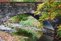 A stone bridge with a creek running under with beautiful reflections in the fall at Indiana University.