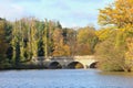 Stone bridge over a lake in the Autumn sunshine with tree leaves Royalty Free Stock Photo