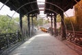 A stone bridge with rain roof and LED light curve crossing a small river