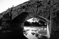 Stone bridge and reflections in a park puddle. Royalty Free Stock Photo