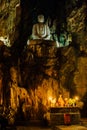 Stone Buddha inside the cave temple above an altar with candles