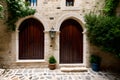 A stone building with two wooden doors and a potted plant. Royalty Free Stock Photo