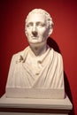 stone bust of Montesquieu with a red background in the museum of Versailles.