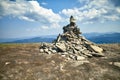 Stone cairn on mountain against blue sky with clouds Royalty Free Stock Photo