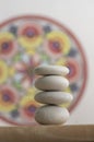 Stone cairn on white and colorfull red yellow mandala background, four stones tower, simple poise stones Royalty Free Stock Photo