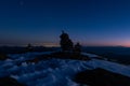 Stone cairns on snowy ground at night under starry sky