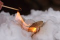 Stone of Calcium carbide calcium acetylide burn with big flame in white snow. Piece of carbide react with water from snow and