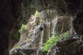 Stone cave landscape with greenery. Ancient cave view to jungle forest. Mountain exploration in tropical nature