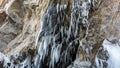 From the stone ceiling of the grotto in granite rock, icicles hang in rows