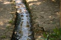 Stone channel in the ground carrying water to the river coming from the mountain. Water and life concept