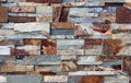 Stone cladding wall made of natural stones of different shapes. The main colors are red, gray,orange and brown.