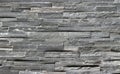 Stone cladding wall made of striped stacked slabs of natural dark gray rocks. Panels for exterior .